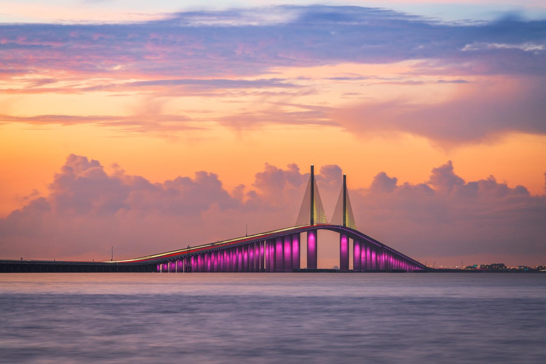 The Sunshine Skyway Bridge glowing pink and purple over Tampa Bay at sunset
