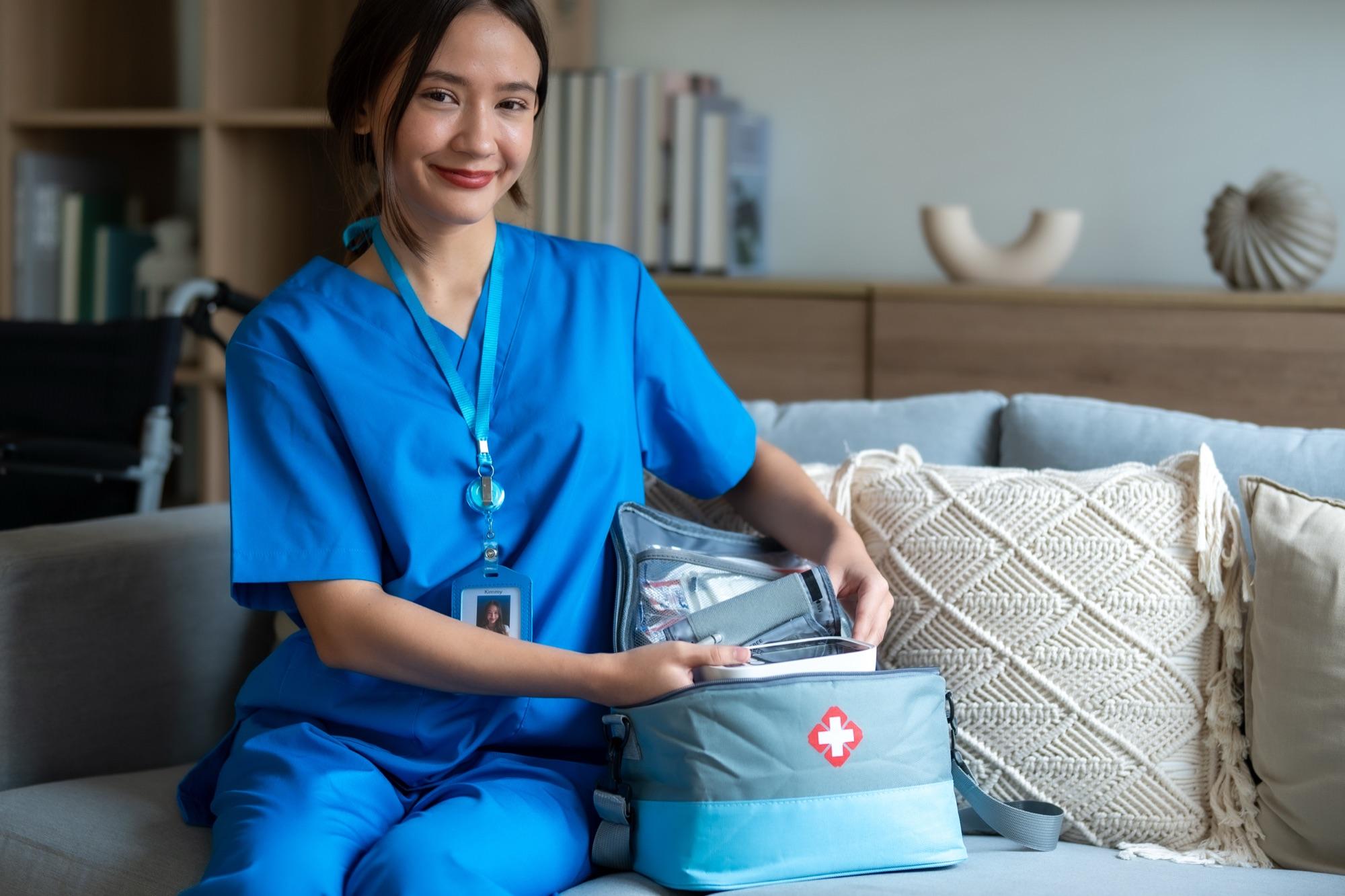 A home health nurse with her visit bag of supplies, smiling in a family's living room